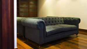A room with a dark blue tufted sofa, wooden flooring, and a wooden wardrobe with glass doors. - Soho Boutique Salamanca  (Salamanca)
