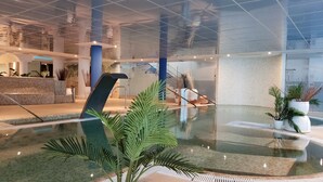 Eine moderne Lobby mit einer zentralen Wasserspende, einem Empfangsbereich und einer Treppe zu den oberen Etagen.