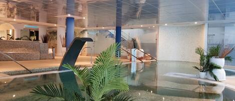 A modern lobby with a central water feature, a reception desk, and a staircase leading to upper floors.