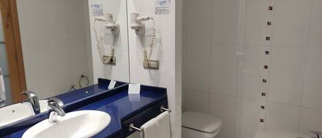 A bathroom with a white sink, a mirror, a toilet, and a bidet.