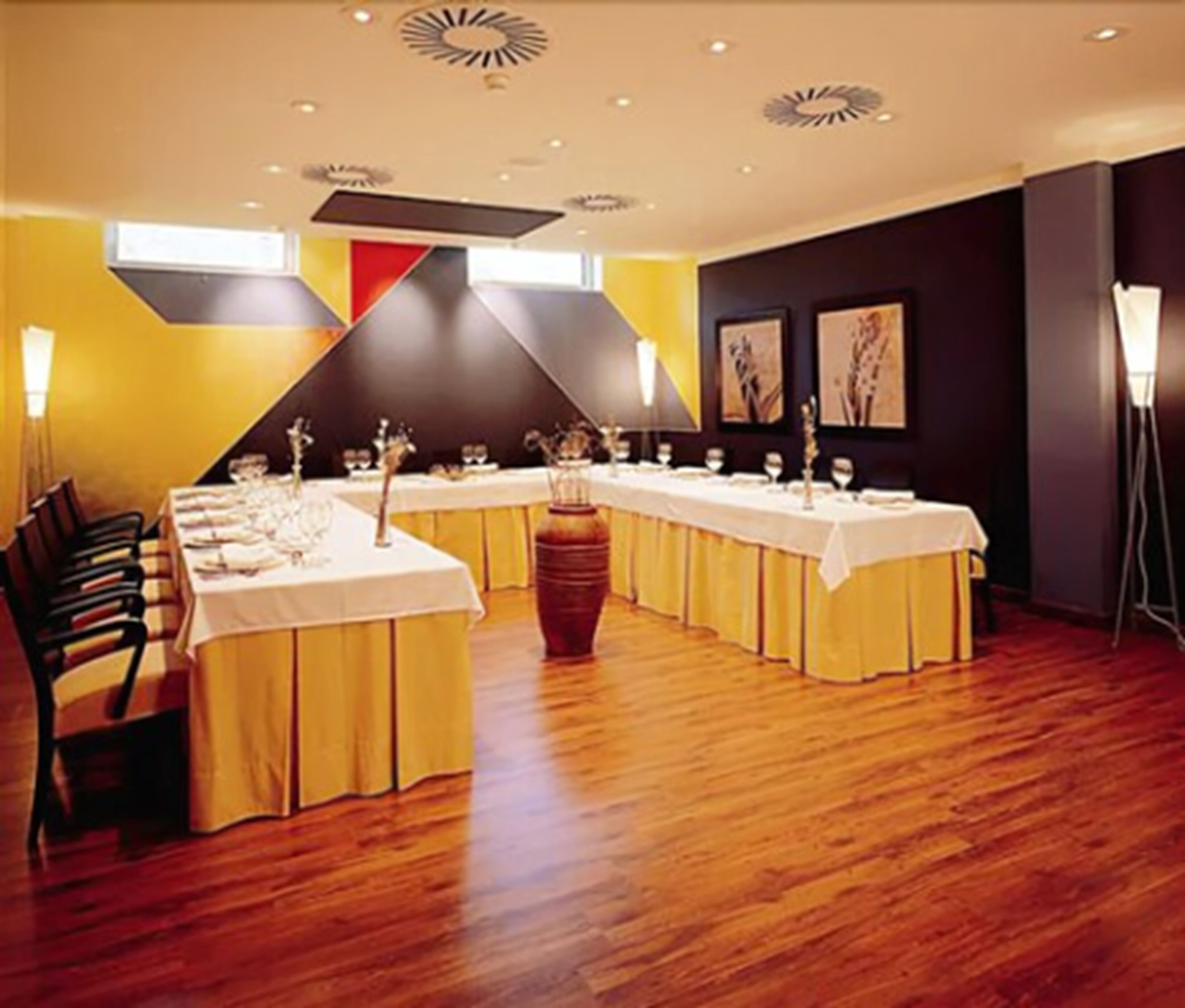 Ein Konferenzraum mit langen Tischen, Stühlen und einer großen Vasen-Mittelstück.