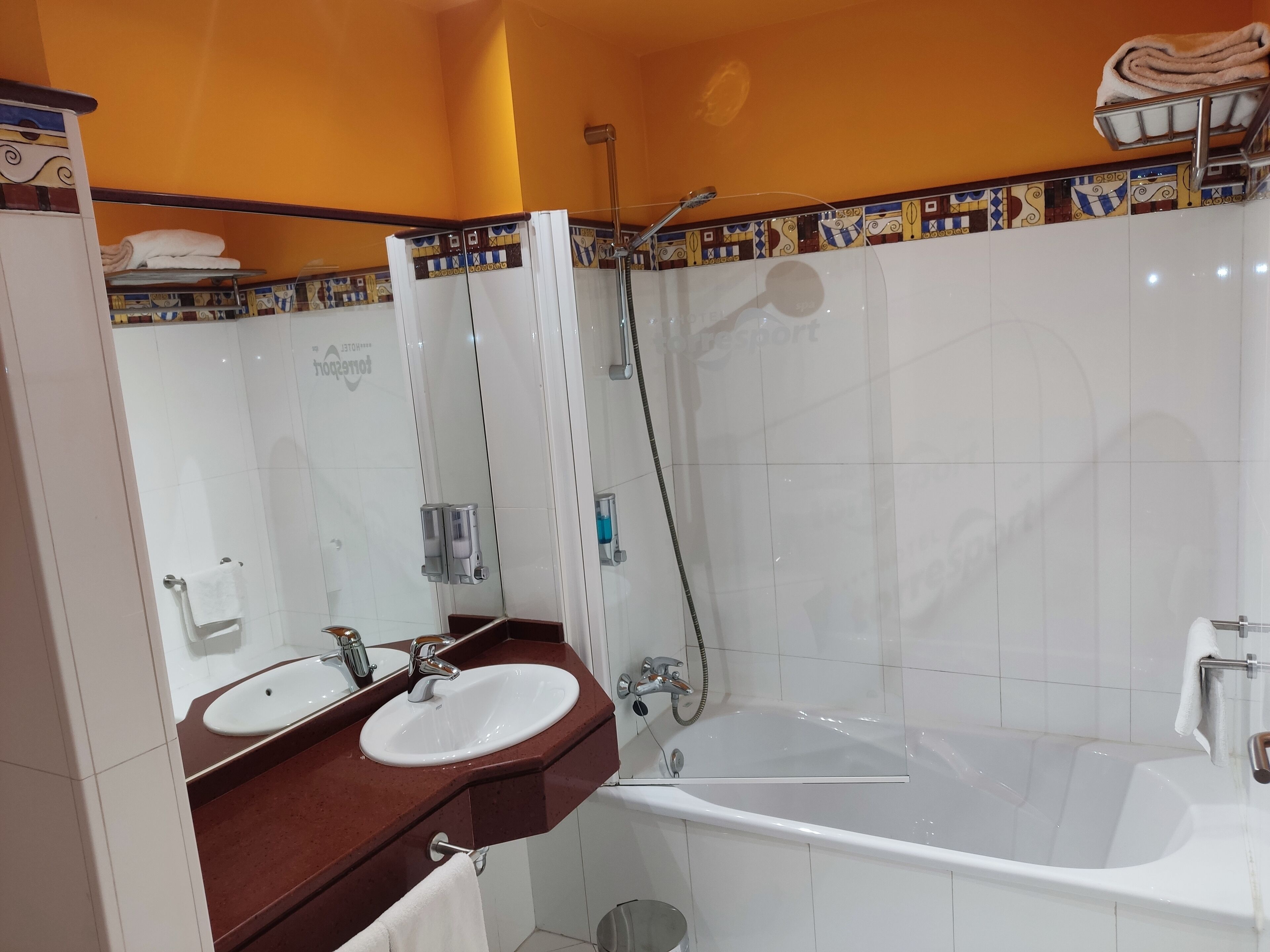 A bathroom with a bathtub, two sinks, a shower, and a towel rack.