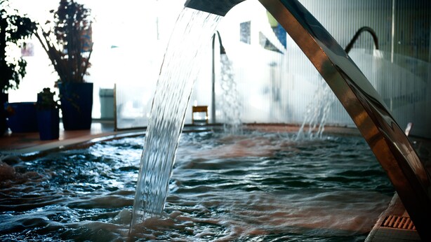 Ein Wasserspiel mit einer gebogenen Metallstruktur und fließendem Wasser.