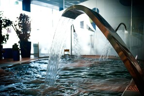 Ein Wasserspiel mit einer gebogenen Metallstruktur und fließendem Wasser.