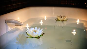 Una bañera con flores de loto y velas.