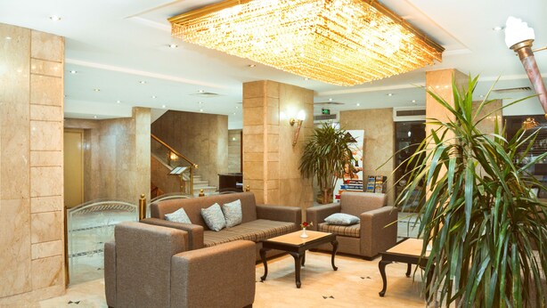 Eine großzügige Lobby mit hoher Decke, einem großen Kronleuchter, bequemen Sitzgelegenheiten und einer Treppe zu einer oberen Etage.