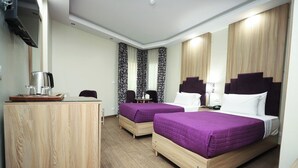 Ein Hotelzimmer mit zwei Betten, einem Schreibtisch, einer Kaffeemaschine und einem Spiegel.
