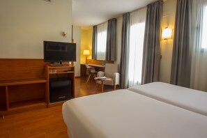 Une chambre d’hôtel avec un grand lit, un bureau avec une chaise, une télévision et un mini-bar.
