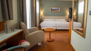 A hotel room with a bed, a chair, a small table, a desk, and a mirror. - Hotel Alaquas (Alaquas)