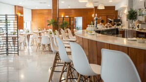 A modern restaurant with a long counter, white chairs, and wooden accents. - Hotel Alaquas (Alaquas)
