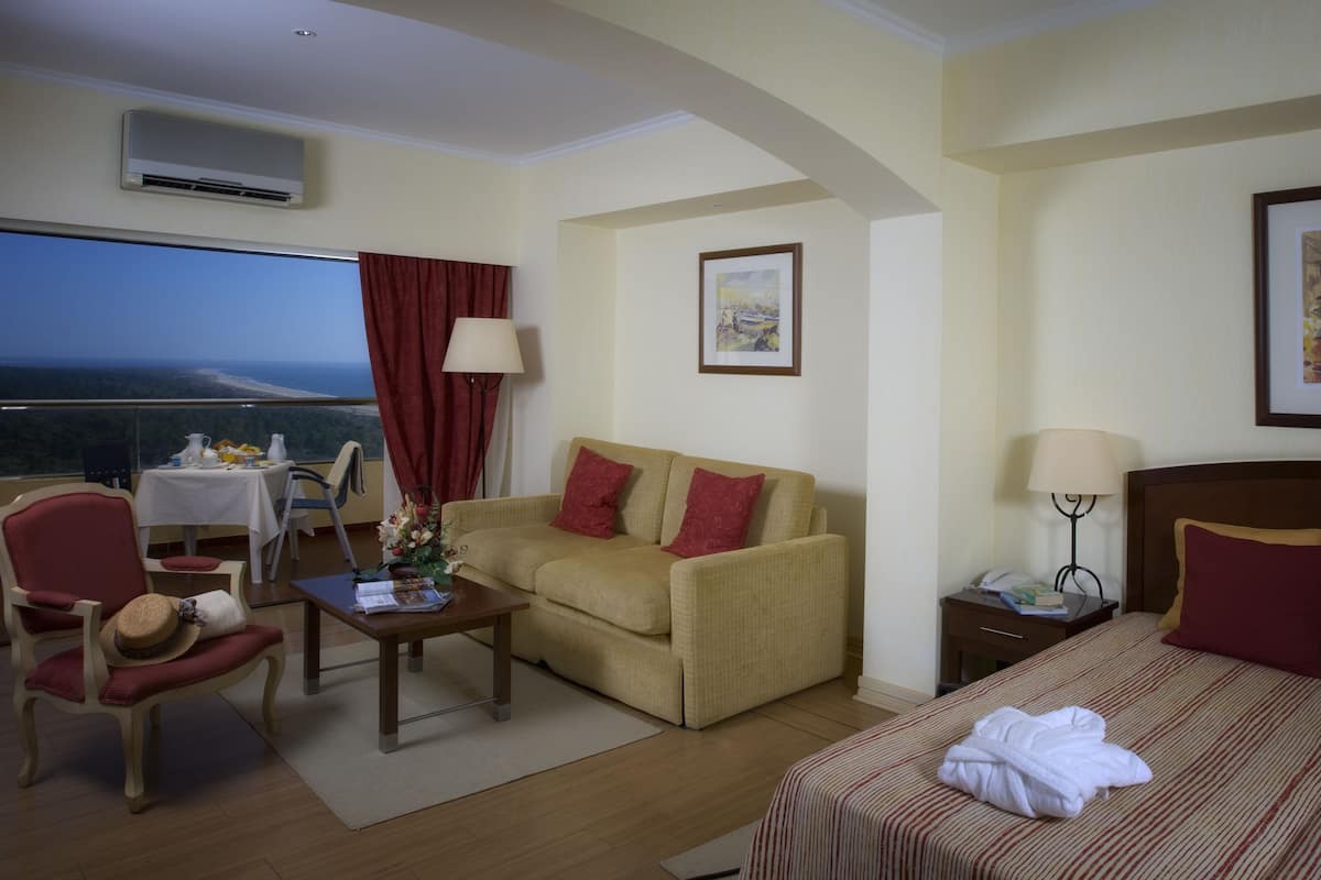 Une chambre d’hôtel avec un balcon, un canapé, un lit, un bureau et une chaise.