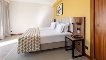 A hotel room with a bed, bedside table, and a wall-mounted phone.