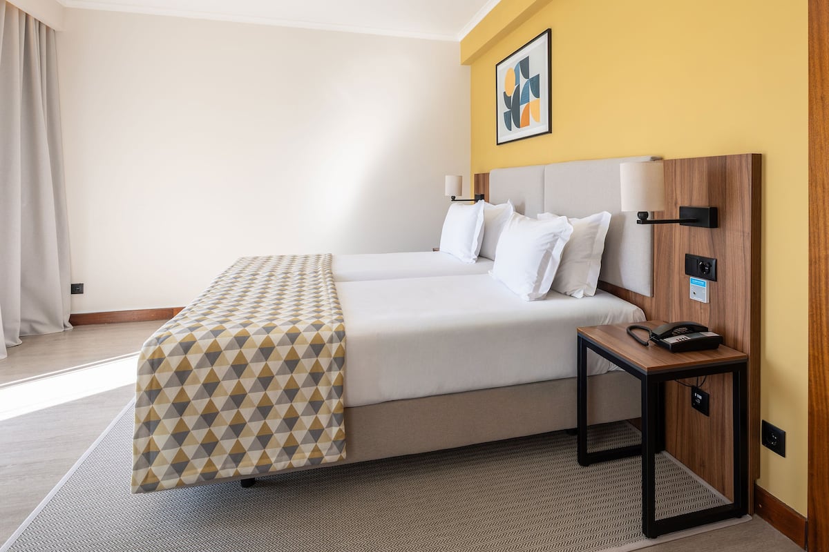 Una habitación de hotel con cama, mesita de noche y teléfono en la pared.