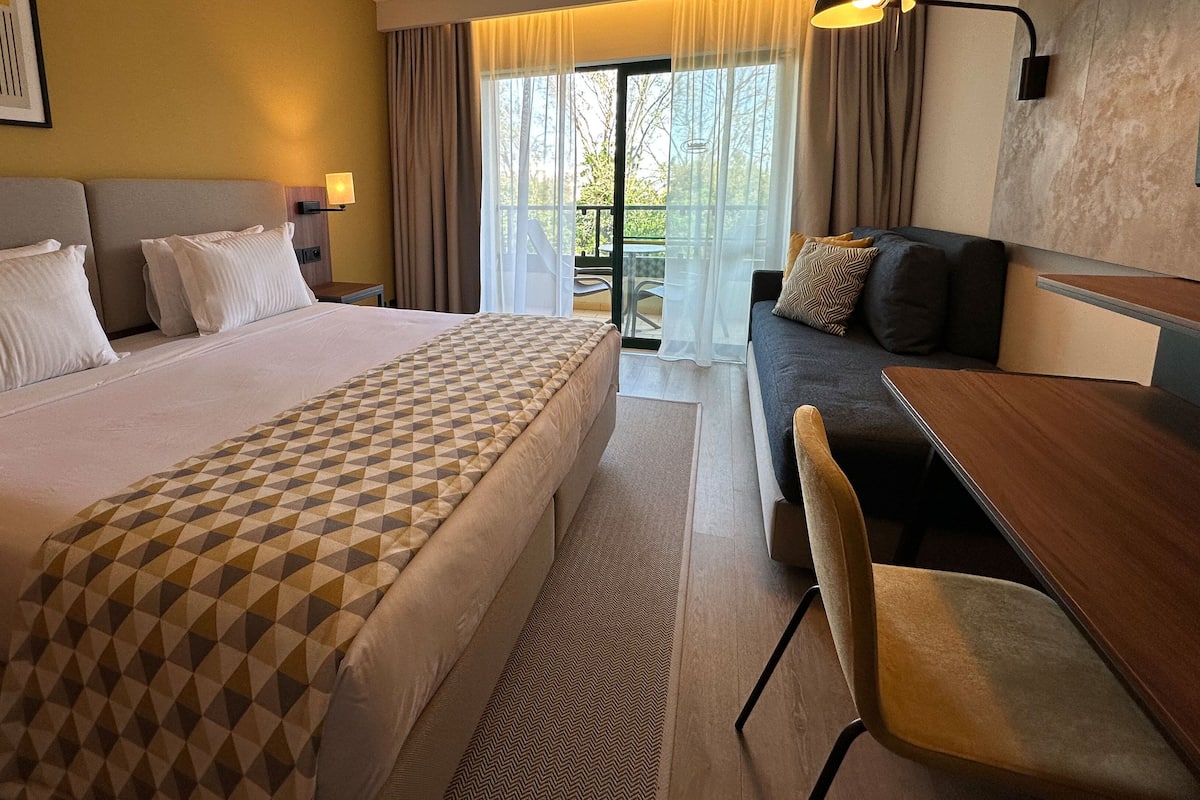 Una habitación de hotel con una cama grande, un sofá, una mesa de comedor y una silla.