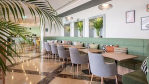 A modern restaurant with green upholstered seating, marble flooring, and pendant lighting. - Holiday Inn Algarve Albufeira by IHG (Albufeira)