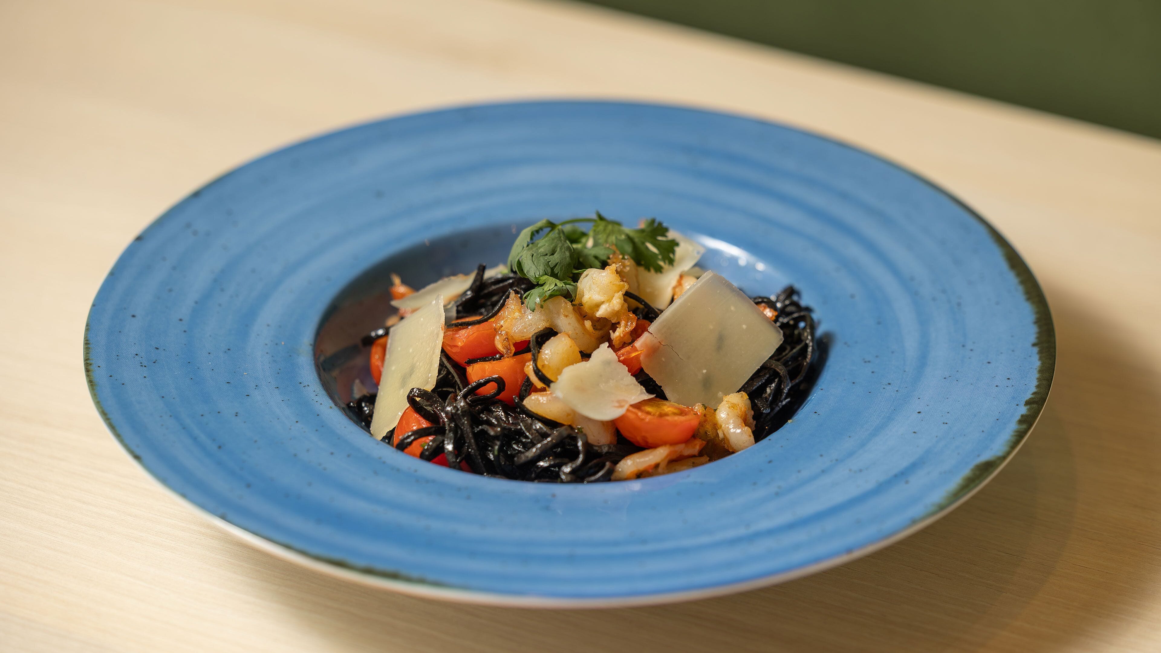 Une assiette bleue contenant un plat composé de légumes et de fromage.