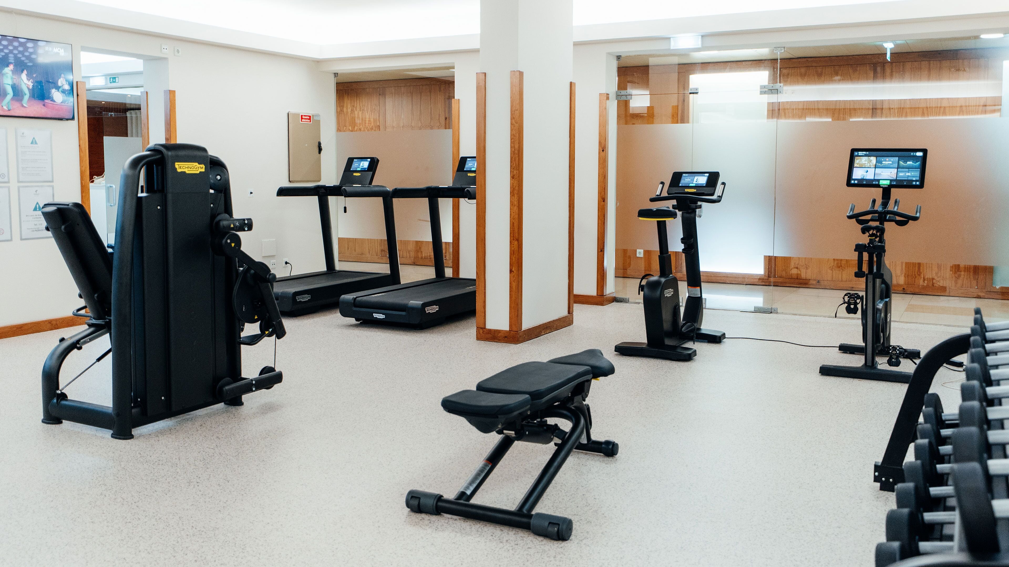 A fitness center with cardio machines, weight training equipment, and a bench.