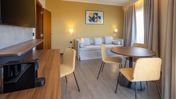 A modern hotel room with a wooden desk, a sofa, and a round dining table.