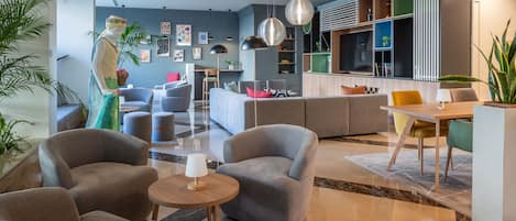 En moderne hotellobby med grå sofaer, et træbord og en stor plante.
