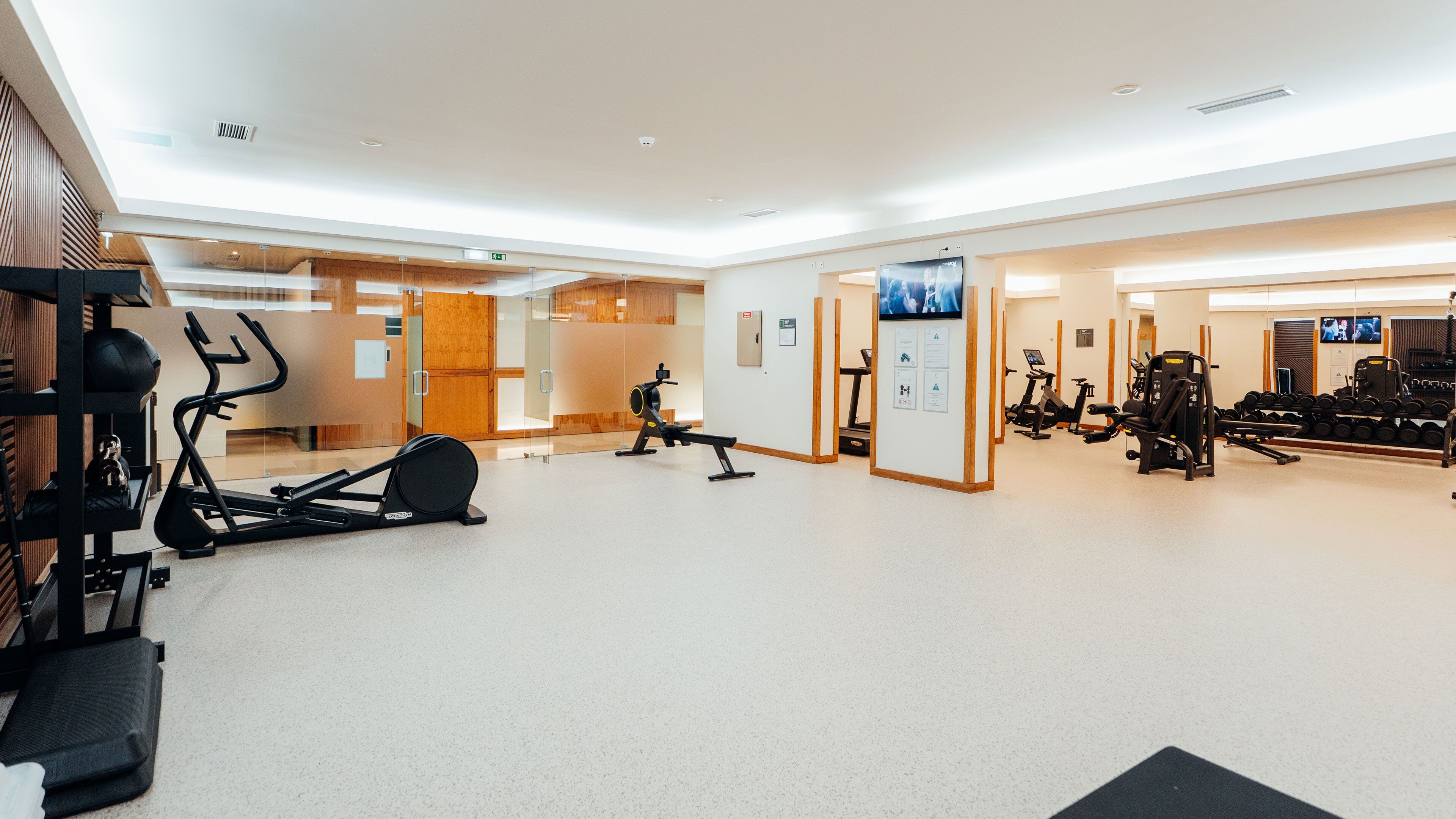 A spacious gym with various exercise equipment, including treadmills, stationary bikes, and weight machines.