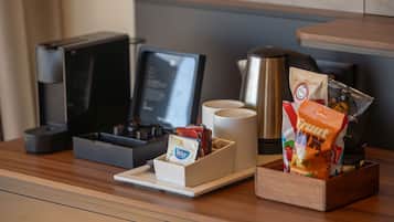 A coffee station with a coffee maker, cups, and snacks.