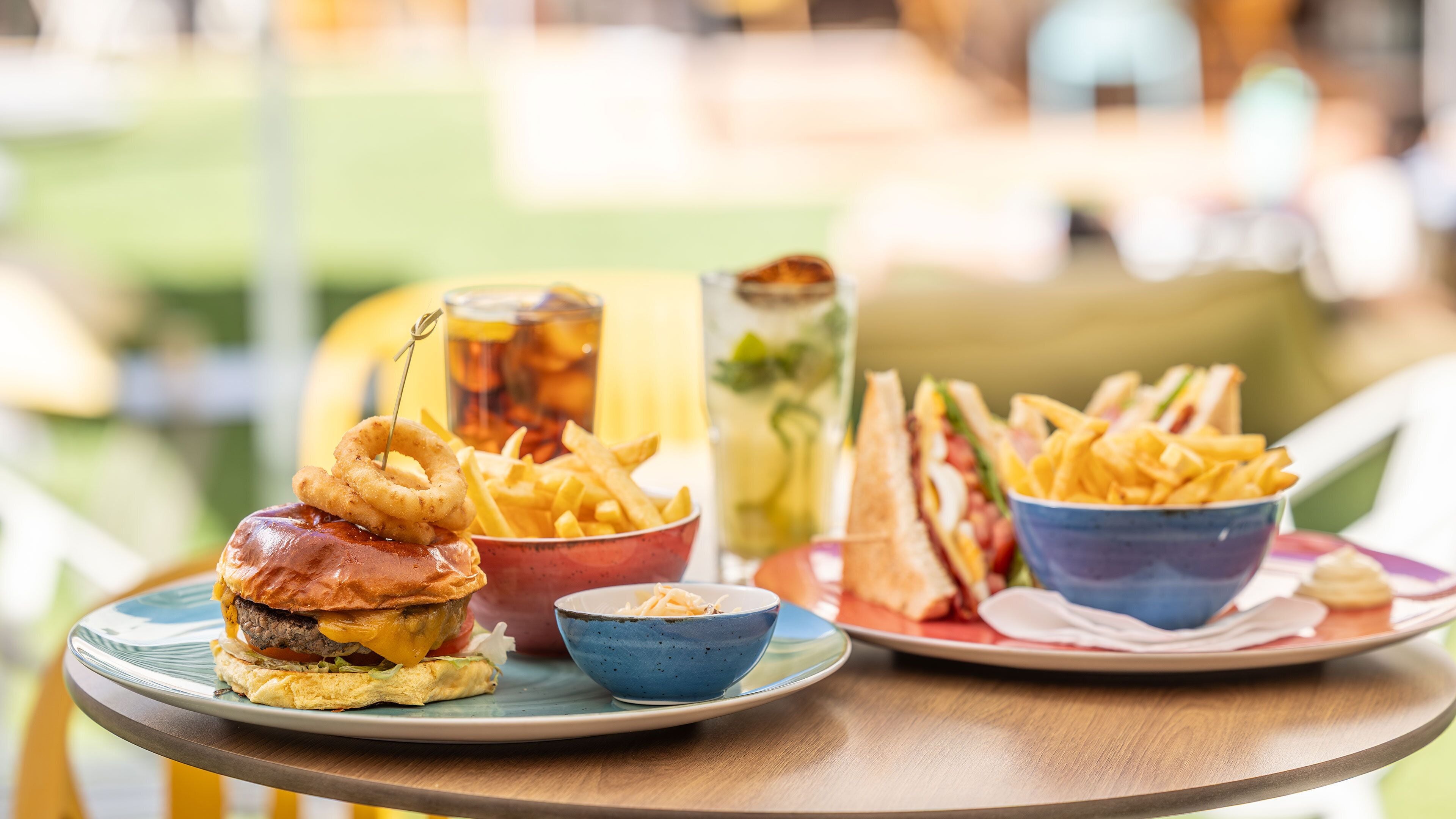 A meal with a burger, onion rings, fries, and a sandwich on a table.