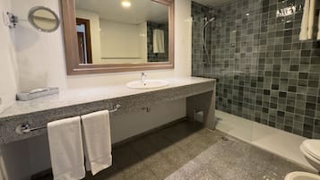 A bathroom with a granite countertop, a sink, a mirror, a towel rack, and a shower area.