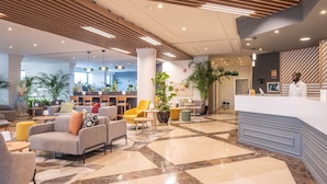 A modern hotel lobby with seating areas, a reception desk, and a view of the lobby in the background. - Holiday Inn Algarve Albufeira by IHG (Albufeira)