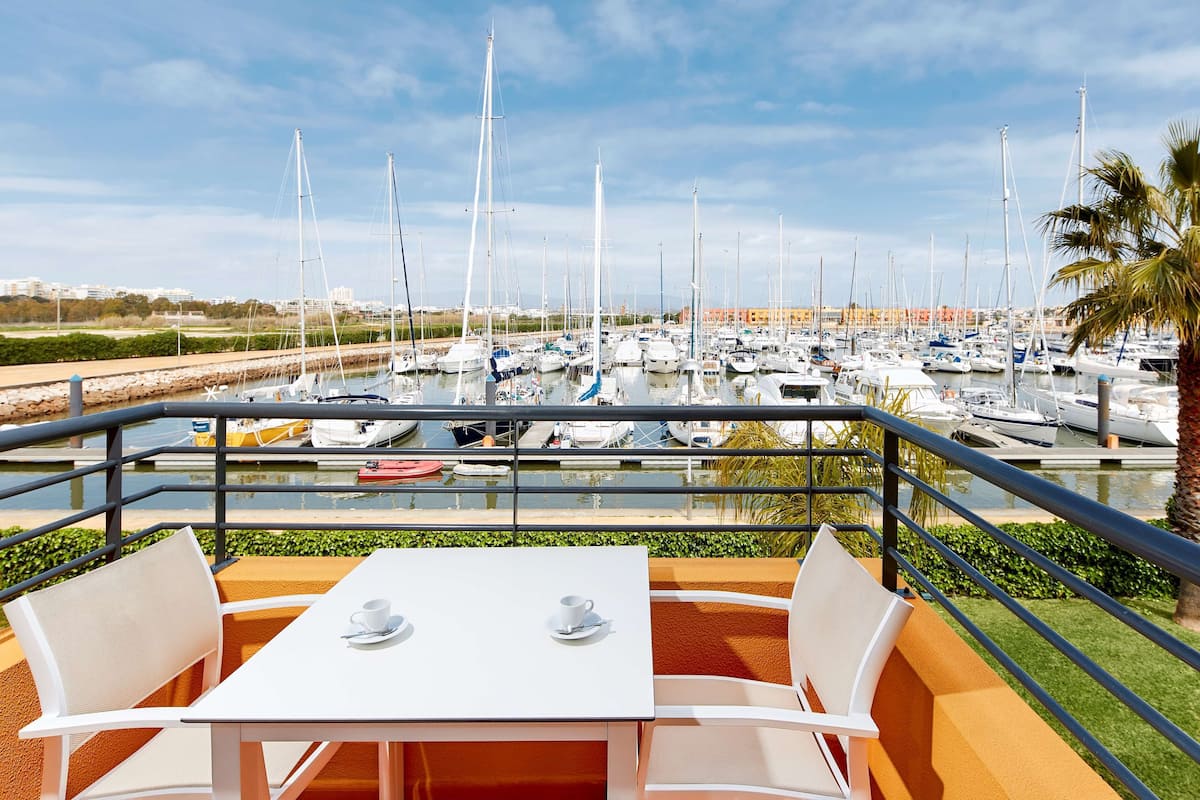 Een eetruimte met een tafel en stoelen, met uitzicht op een jachthaven vol boten.