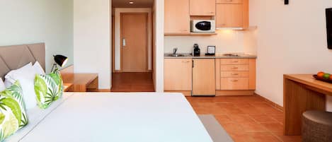 Una habitación de hotel con cama, escritorio, kitchenette y baño.