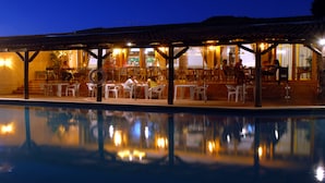 A poolside area with outdoor seating and a covered patio. - Hotel Pinhal do Sol (Loulé)