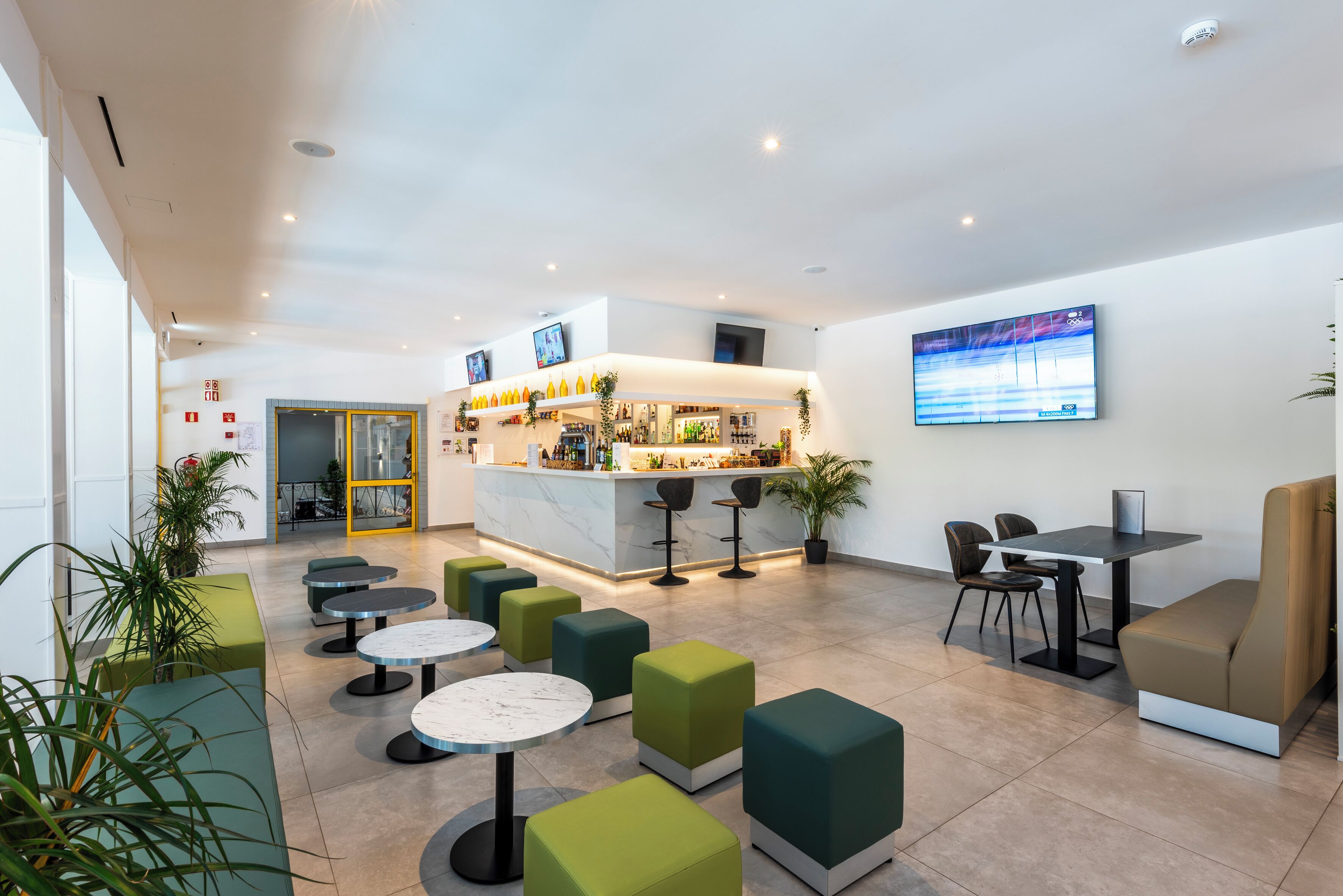 Un moderno vestíbulo con una zona de bar, asientos y una pantalla de televisión.