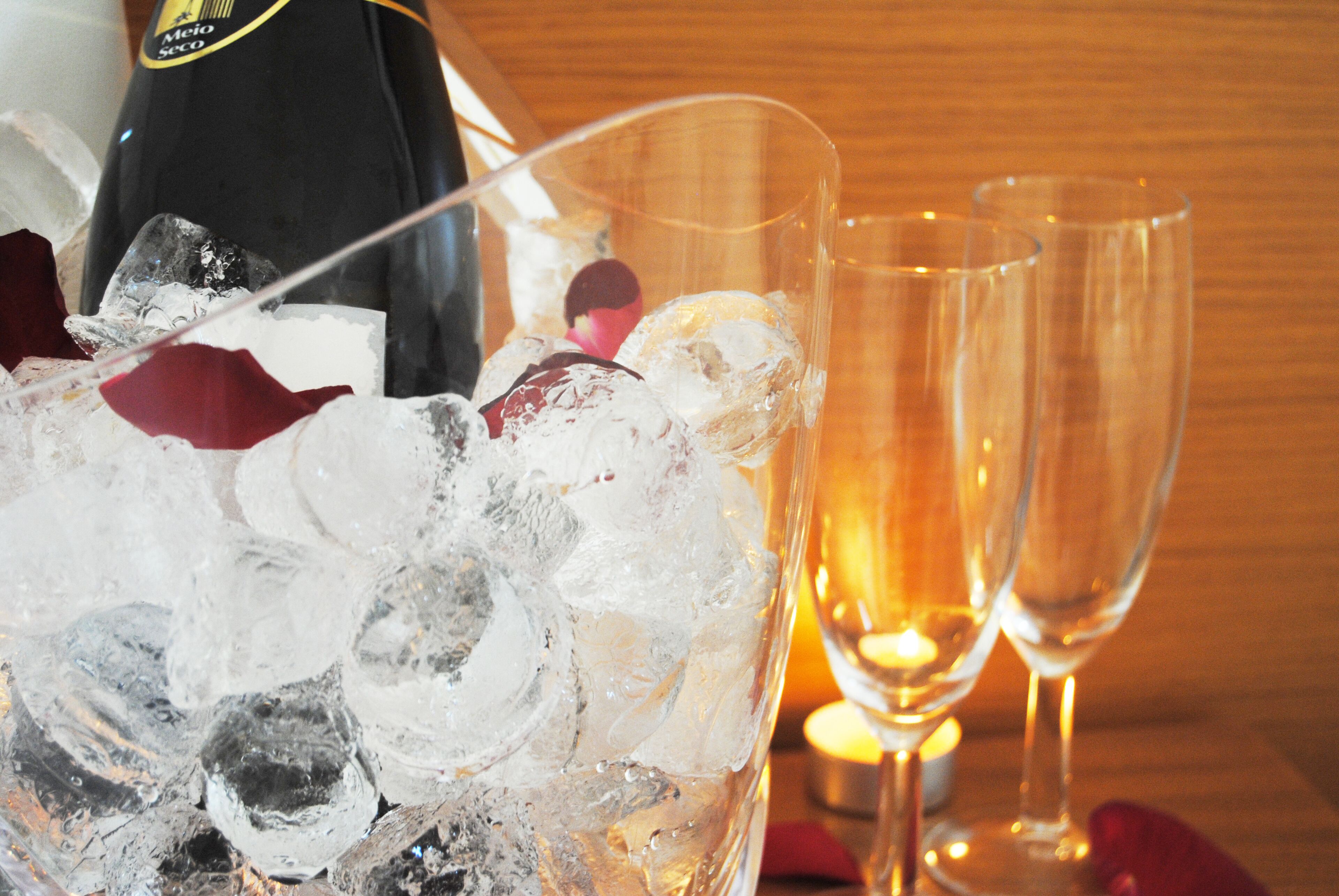 A glass filled with ice cubes and a bottle of wine, with two empty glasses beside it.