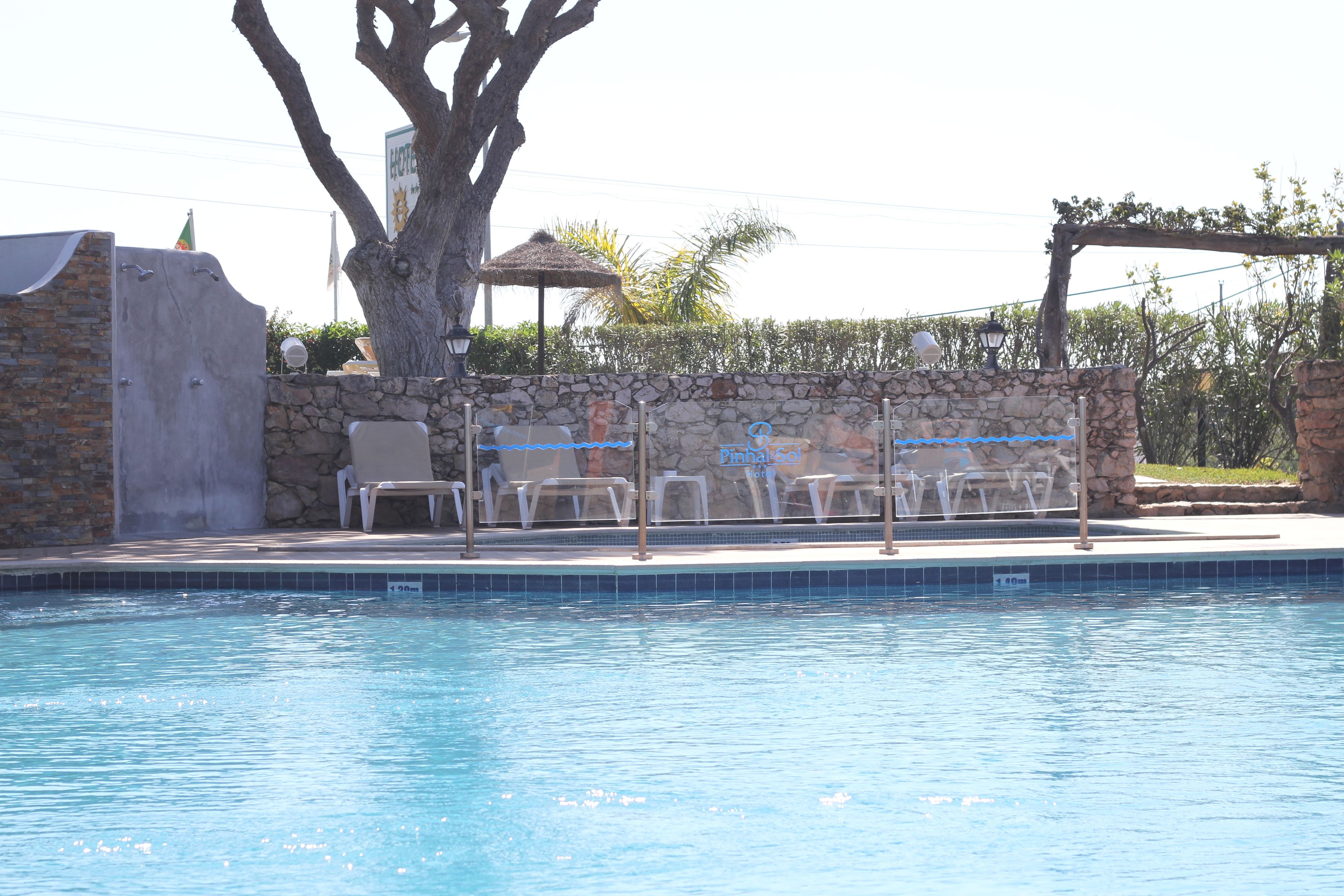 Piscina com espreguiçadeiras e uma parede de pedra.