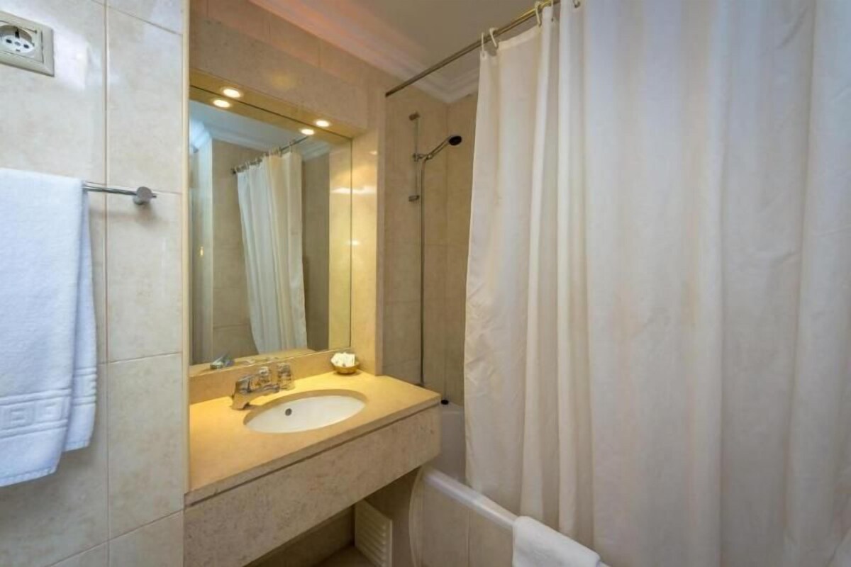 A bathroom with a sink, mirror, and shower curtain.