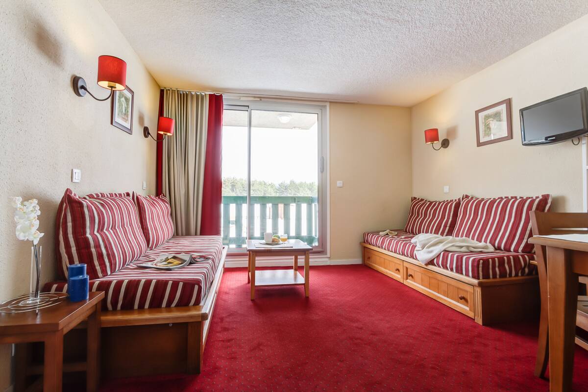 A cozy living room with striped sofas, a wooden coffee table, and a red carpet.