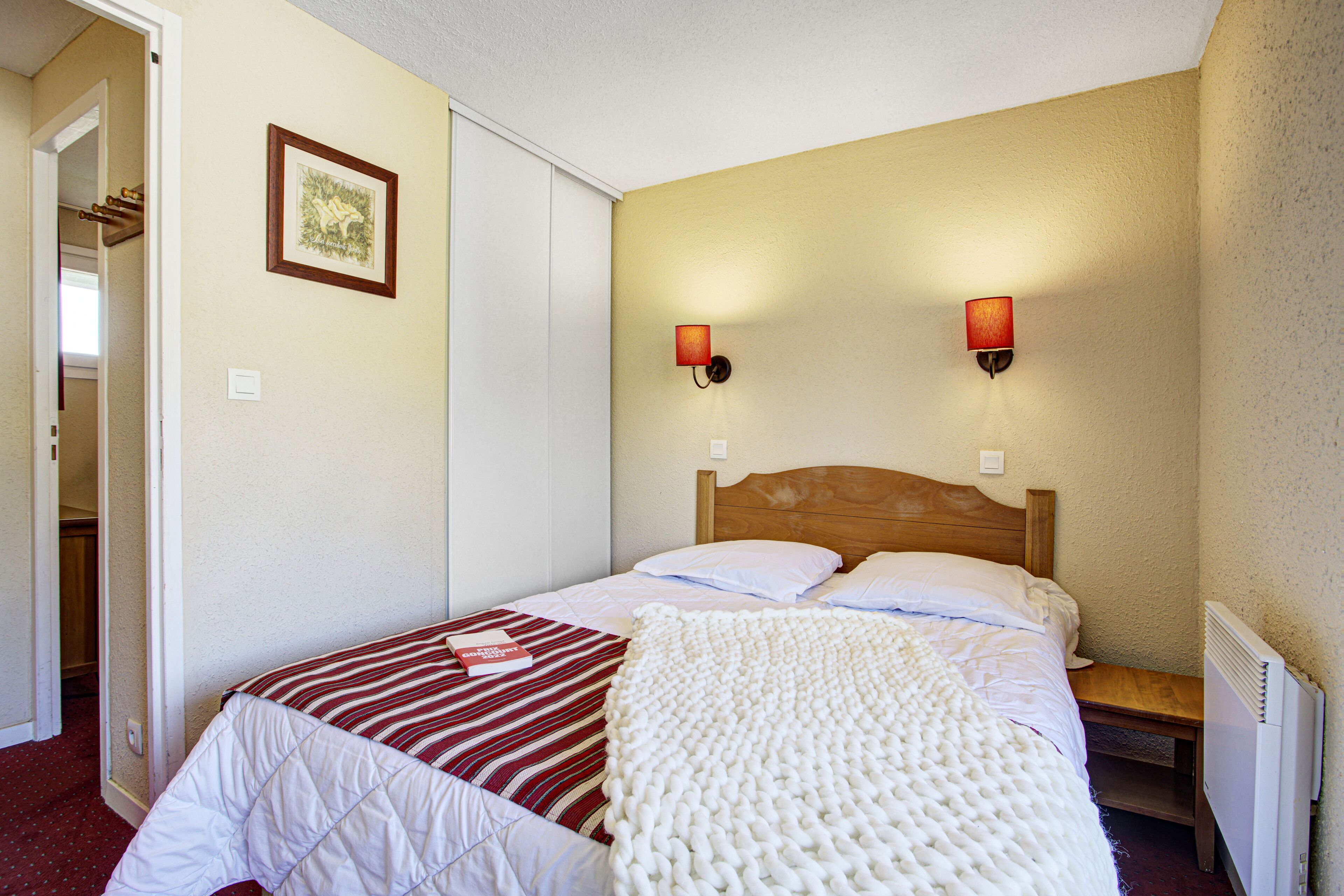 A bedroom with a bed, a bedside table, a lamp, and a framed picture on the wall.