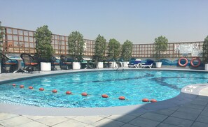 Ein Schwimmbad mit Liegestühlen und Pflanzen in Töpfen.