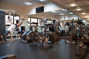 Ein Fitnessstudio mit unterschiedlichen Trainingsgeräten, darunter Laufbänder, Ergometer und Kraftgeräte.