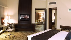 Habitació d'hotel amb un llit, escriptori amb cadira, televisió i un sofà al fons.