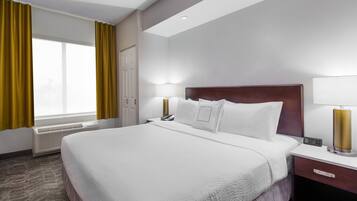 A hotel room with a large bed, bedside lamps, a nightstand, and a window with curtains.
