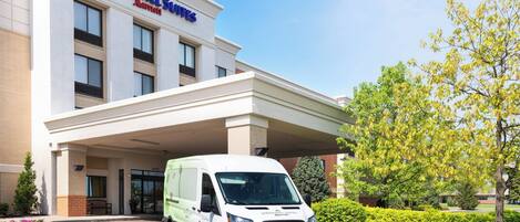 A white van parked in front of a hotel with a sign reading "Springhill Suites."