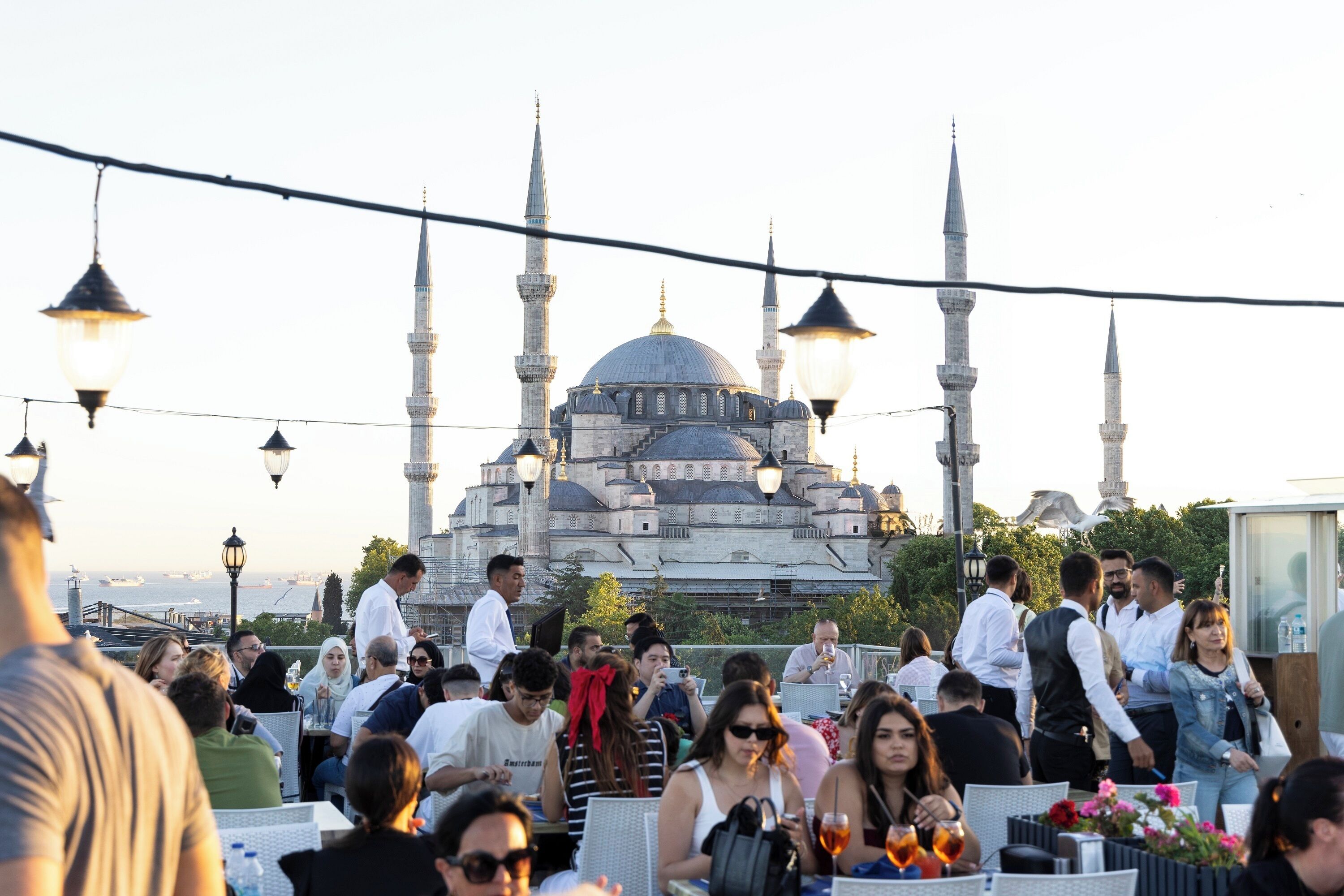 A group of people dining outdoors with a mosque in the background.