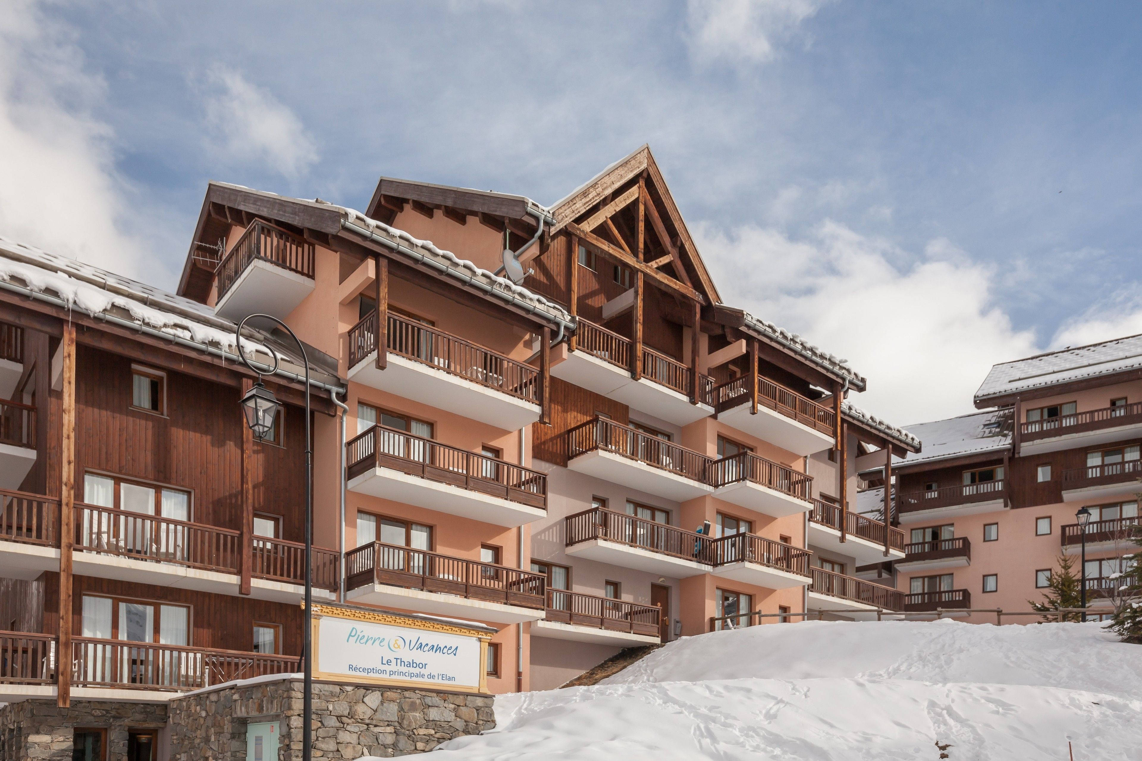 A multi-story hotel with wooden balconies and a sign indicating it is a vacation rental.
