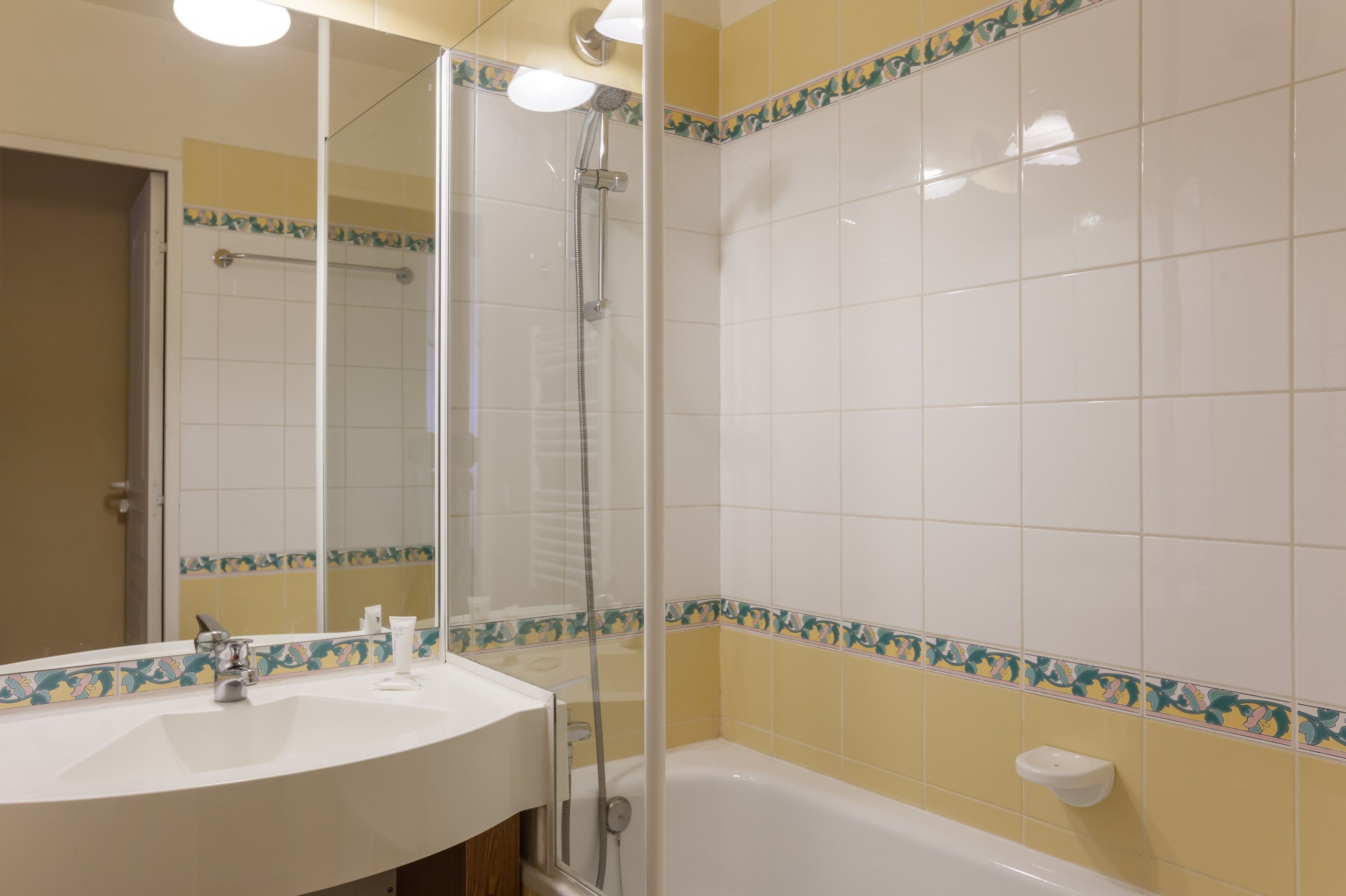Un baño con un lavamanos blanco, ducha con mampara de vidrio y bañera.