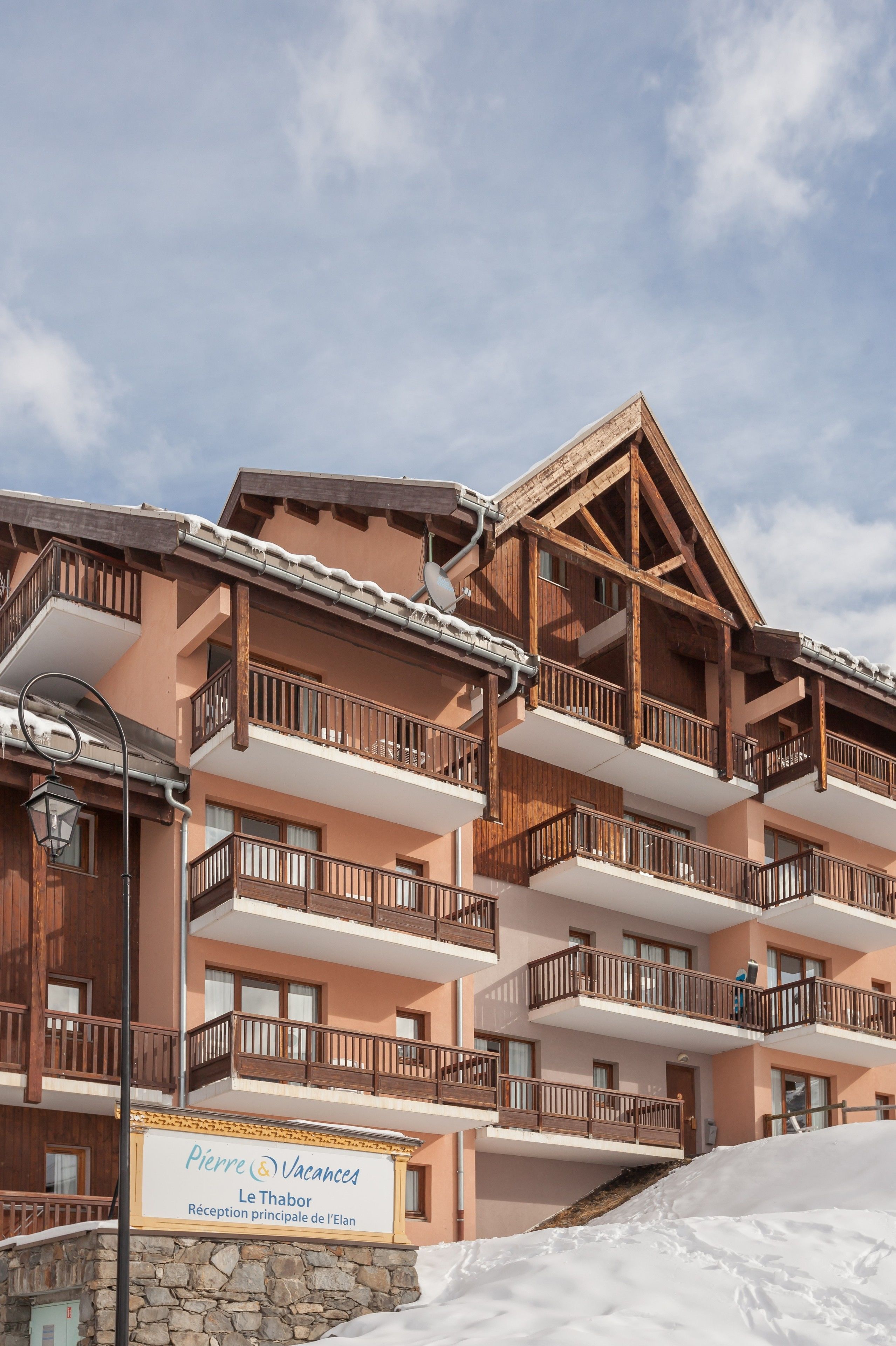 A multi-story building with balconies, a stone base, and a sign indicating it is a reception for the Elan hotel.