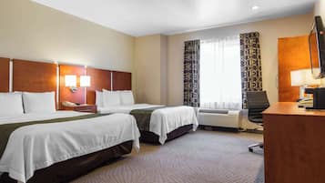 Ein Hotelzimmer mit zwei Betten, einem Schreibtisch, einem Stuhl, einem Telefon und einem Vorhangfenster.