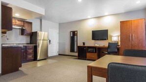 Une chambre d’hôtel compacte dotée d’une kitchenette, d’un coin repas, d’un téléviseur à écran plat et d’une grande armoire.
