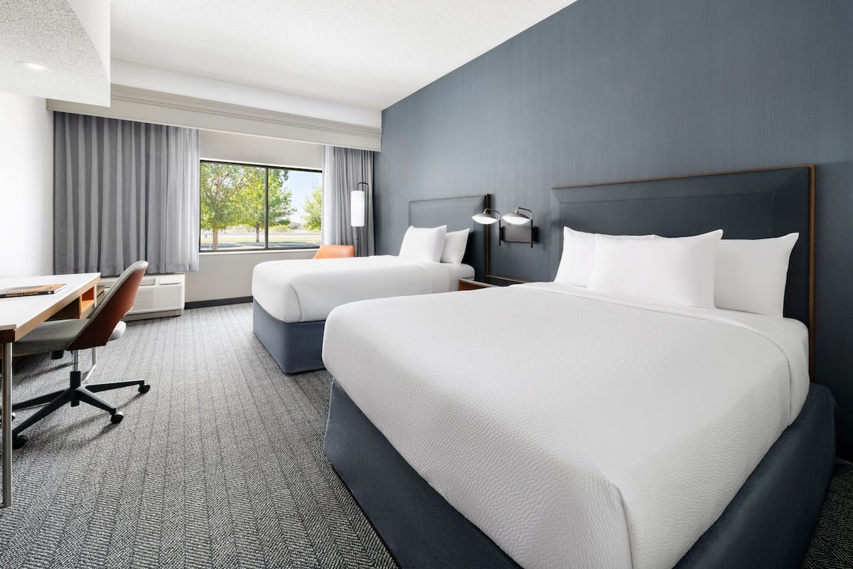 Ein Hotelzimmer mit zwei Betten, einem Schreibtisch und einem Stuhl.