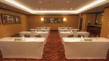 A conference room with tables set for meetings, equipped with chairs, water bottles, and apples.